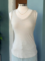 Beige tank top on a mannequin against a blue wall