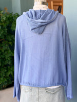 Blue textured sweater on a mannequin with a blurred indoor background