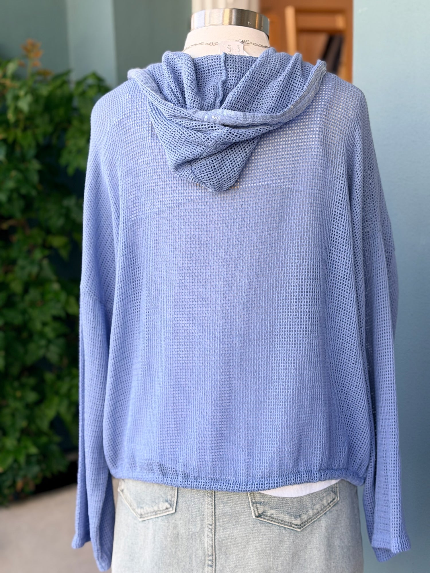 Blue textured sweater on a mannequin with a blurred indoor background