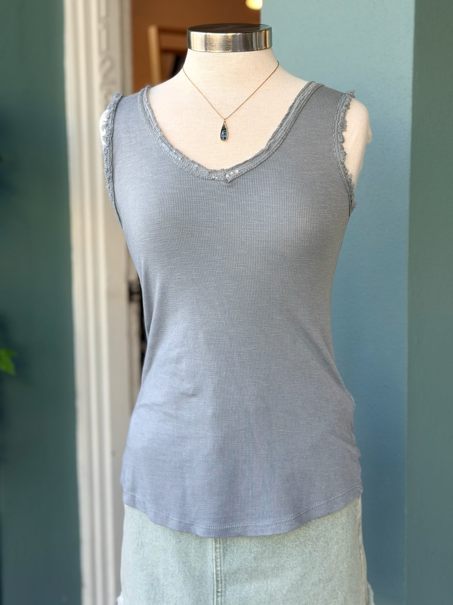 Blue grey sleeveless tank top with subtle sequin-trimmed V-neckline on a mannequin