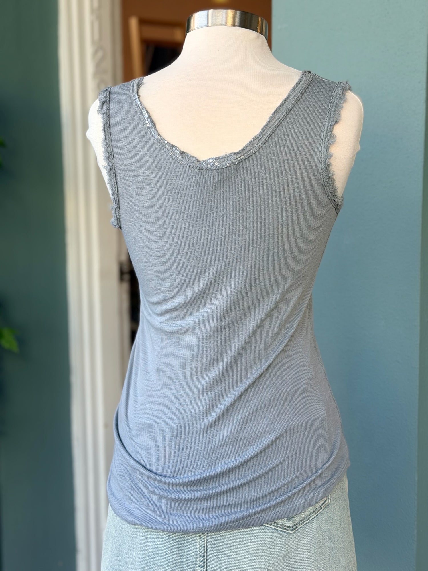 Gray tank top on a mannequin against a blue wall