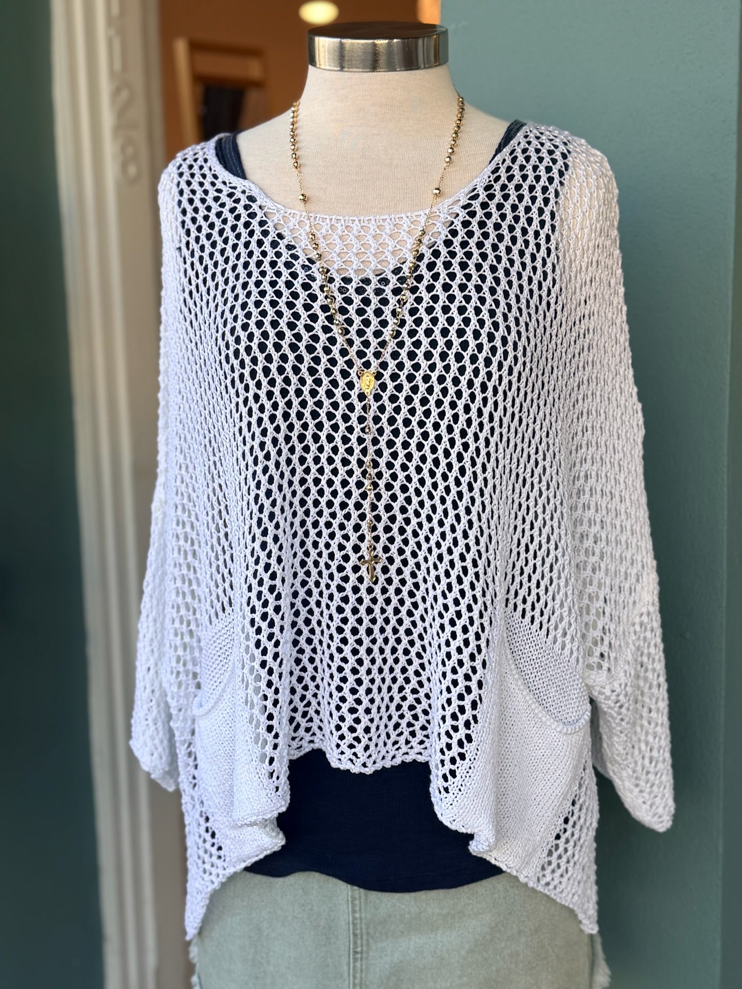 White mesh top on a mannequin against a green wall