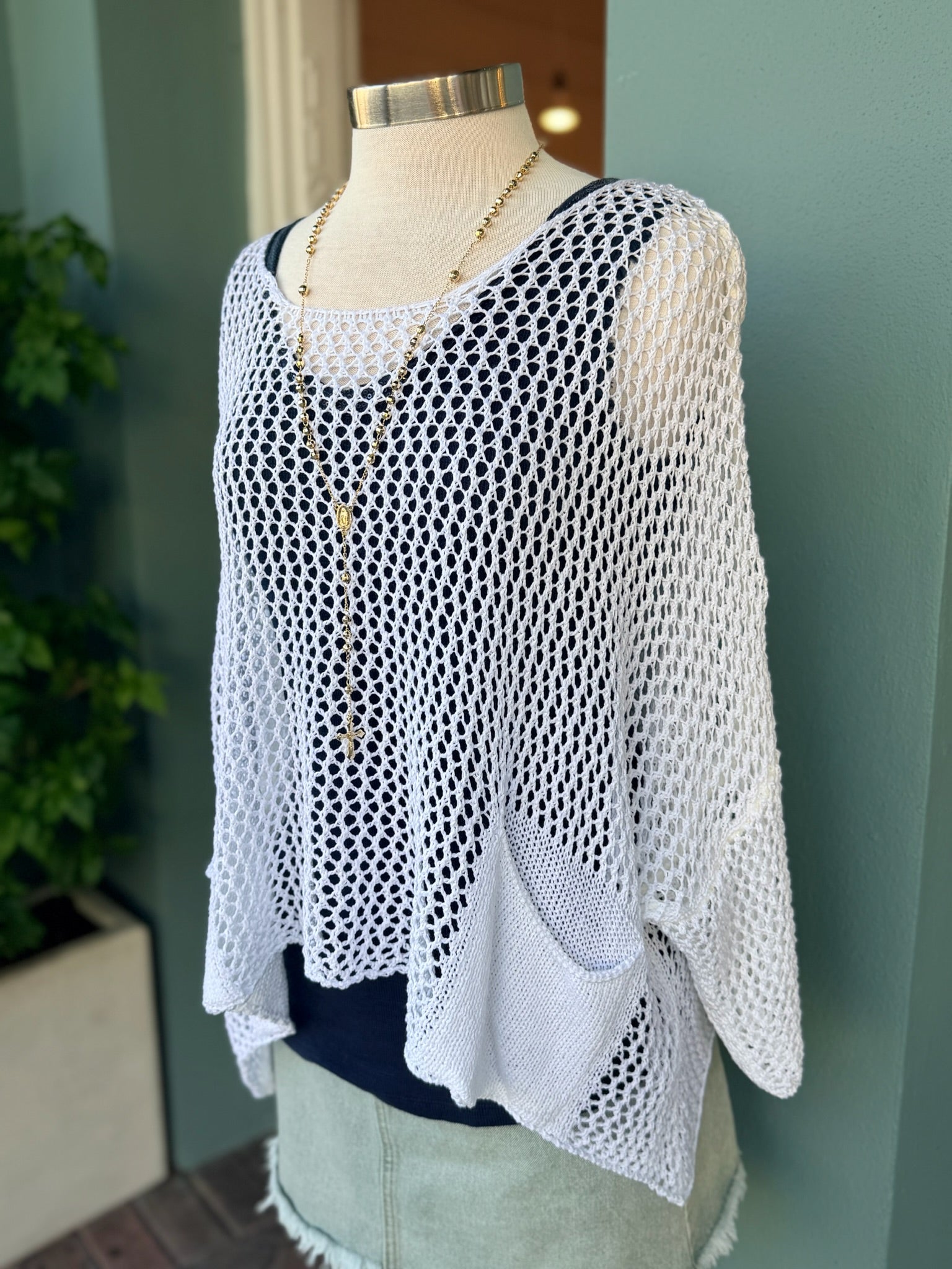 White knit top on a mannequin against a neutral background