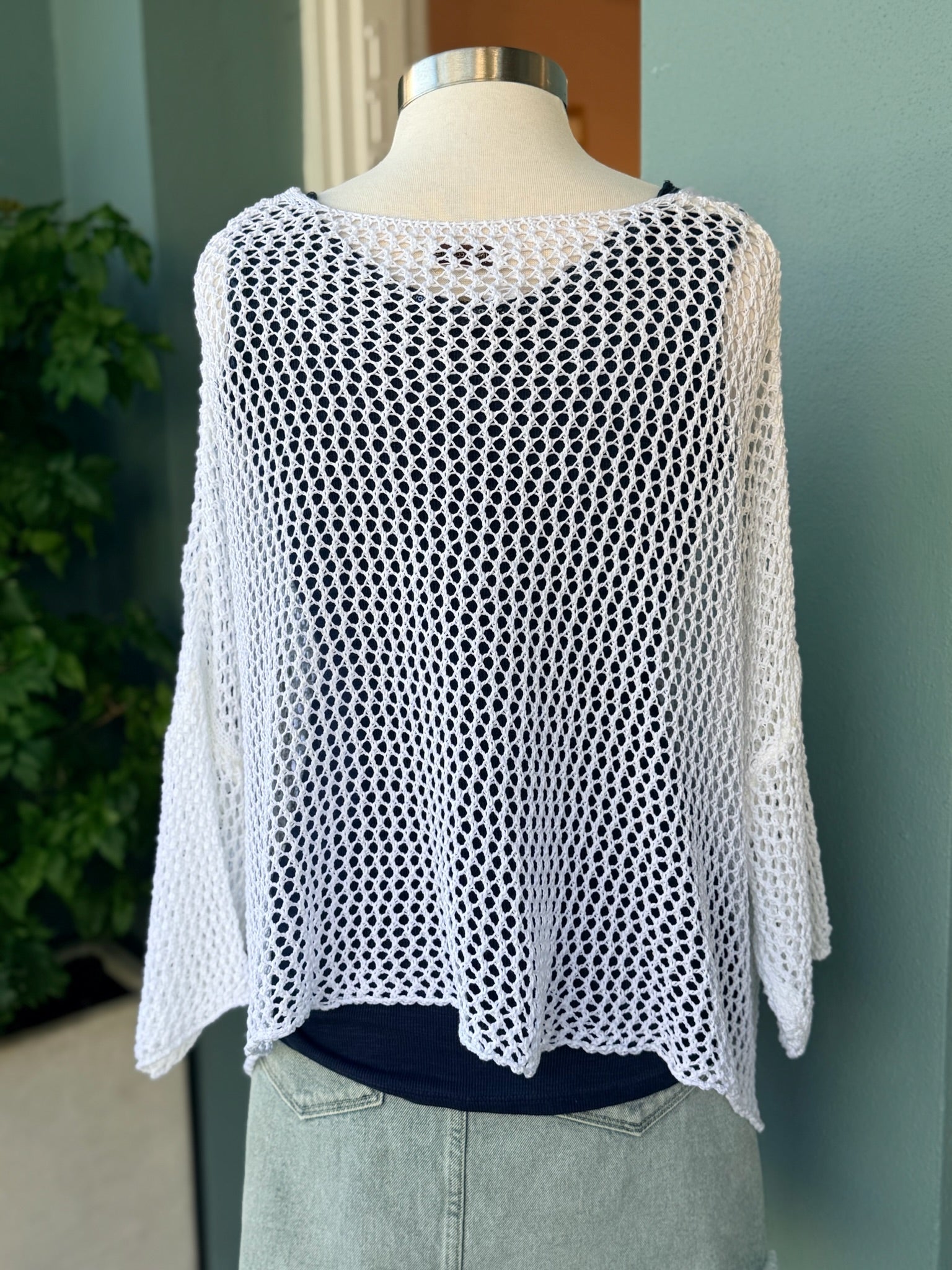 White crochet top on a mannequin against a neutral background