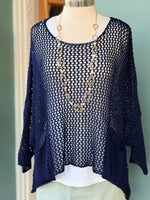 Navy blue knit cardigan on a mannequin with gold necklace against a green wall.