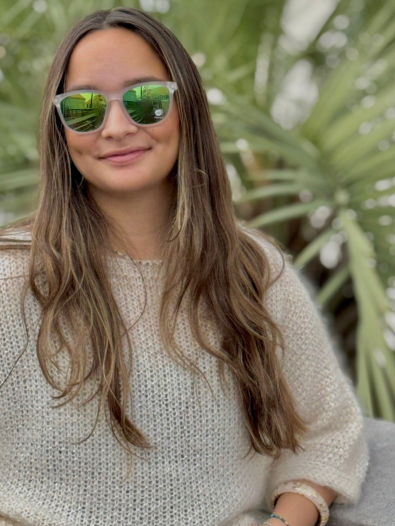 Woman wearing sunglasses with a blurred green leafy background