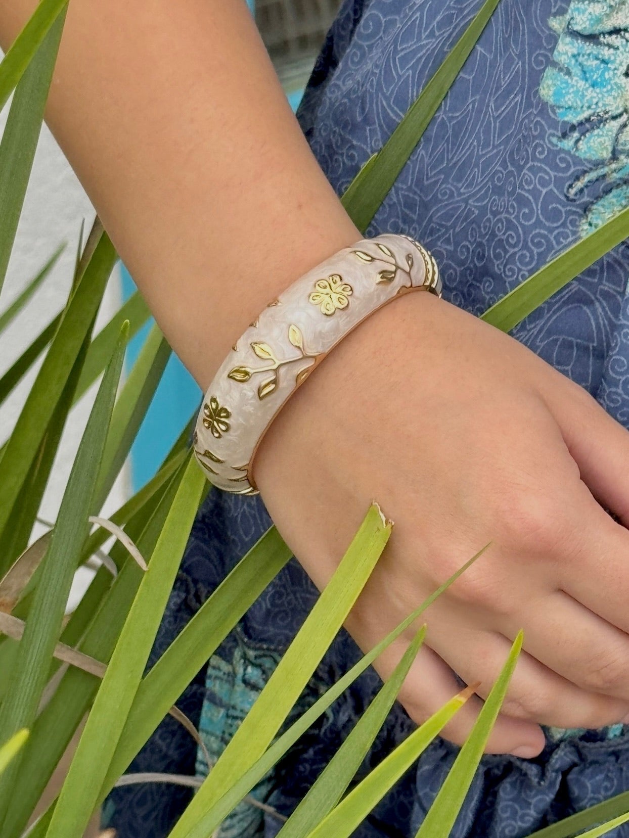 "Elise cloisonné bracelet worn at the beach – dove grey enamel with gold flowers"