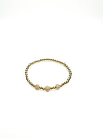 Gold bracelet with three beads on a white background