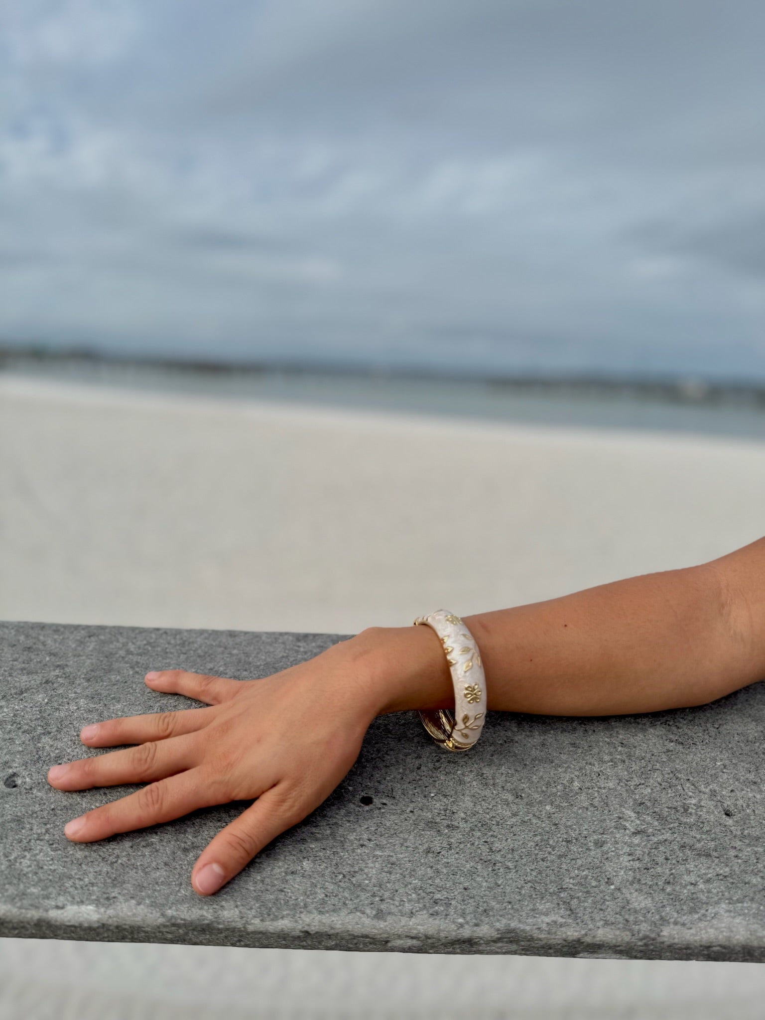 "Elise cloisonné bracelet worn at the beach – dove grey enamel with gold flowers