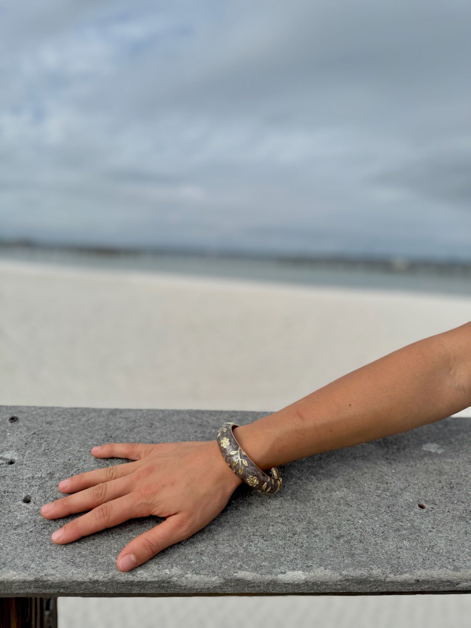“Elise cloisonné bracelet worn at the beach – brown enamel with gold flowers”