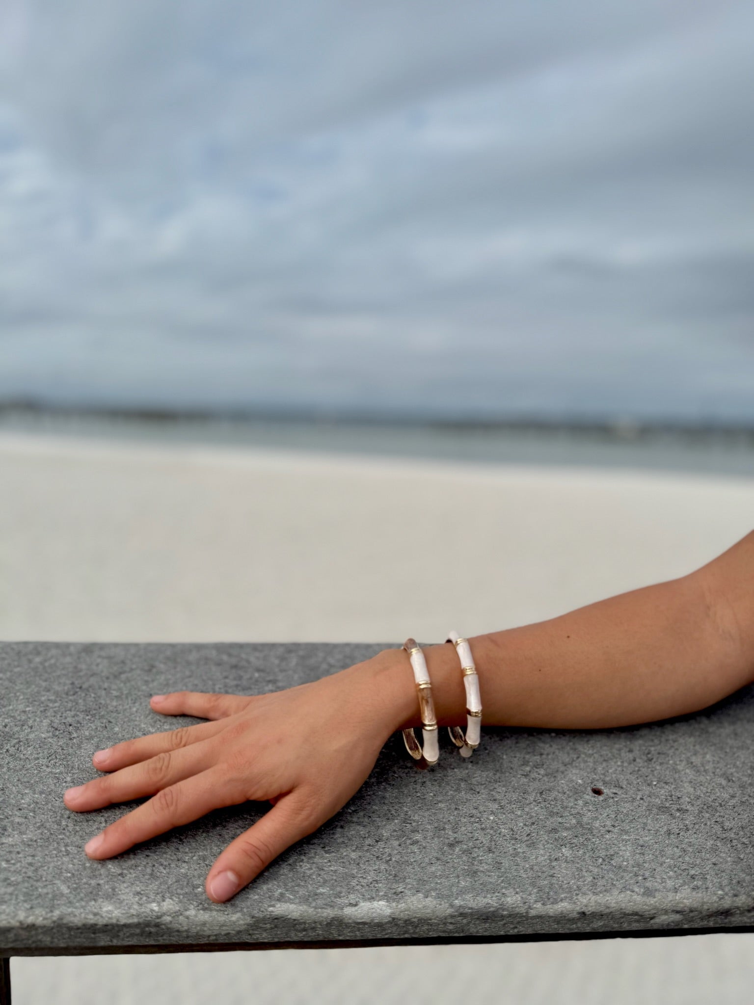 "Camille cloisonné bracelet worn at the beach – subtle ivory and taupe enamel tones"