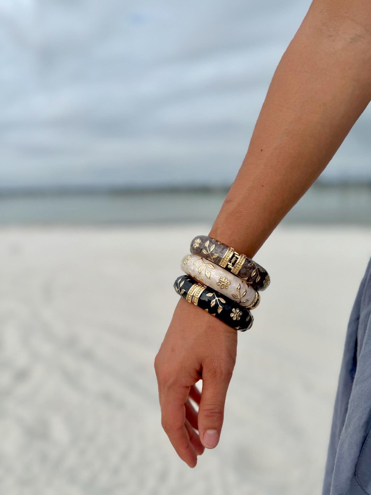 "Elise cloisonné bracelet worn at the beach – dove grey enamel with gold flowers"
