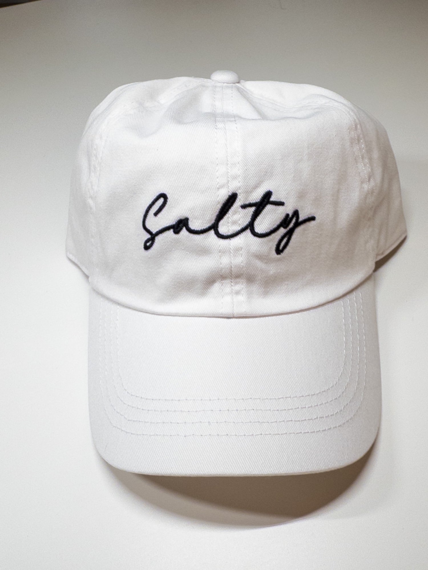White cap with 'Salty' embroidery on a white background