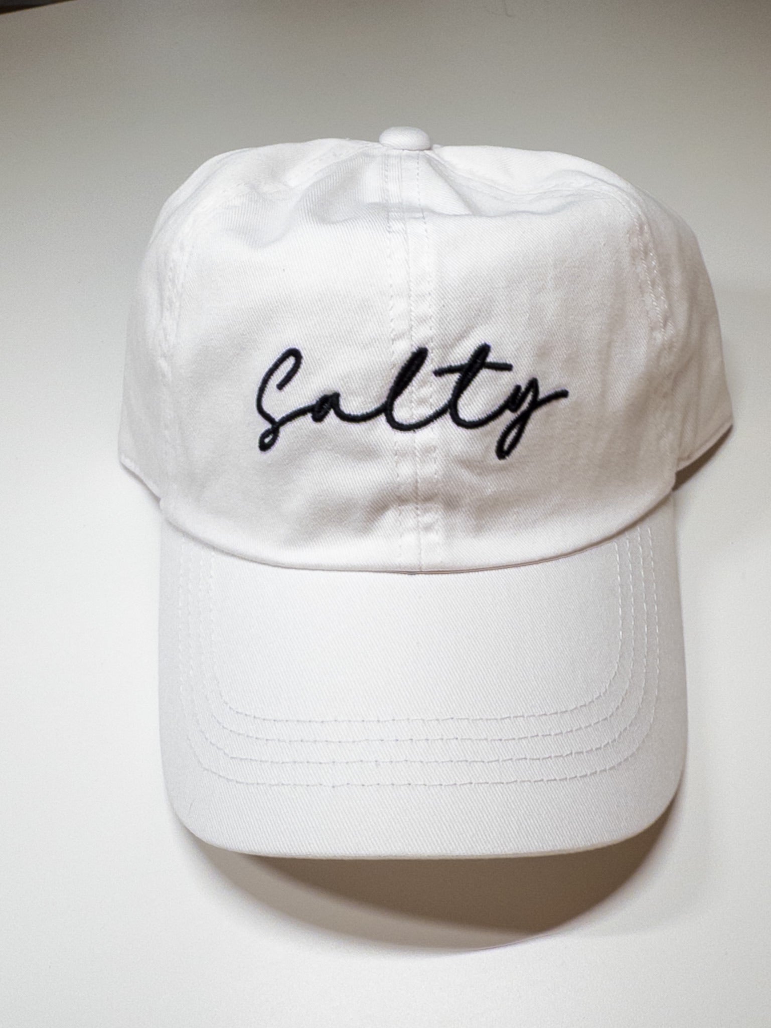 White cap with 'Salty' embroidery on a white background