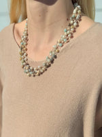 Necklace with multicolored beads worn by a person in a beige sweater.