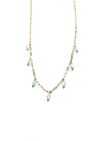 Delicate gold chain necklace with seafoam green bead drops laid flat on a white background
