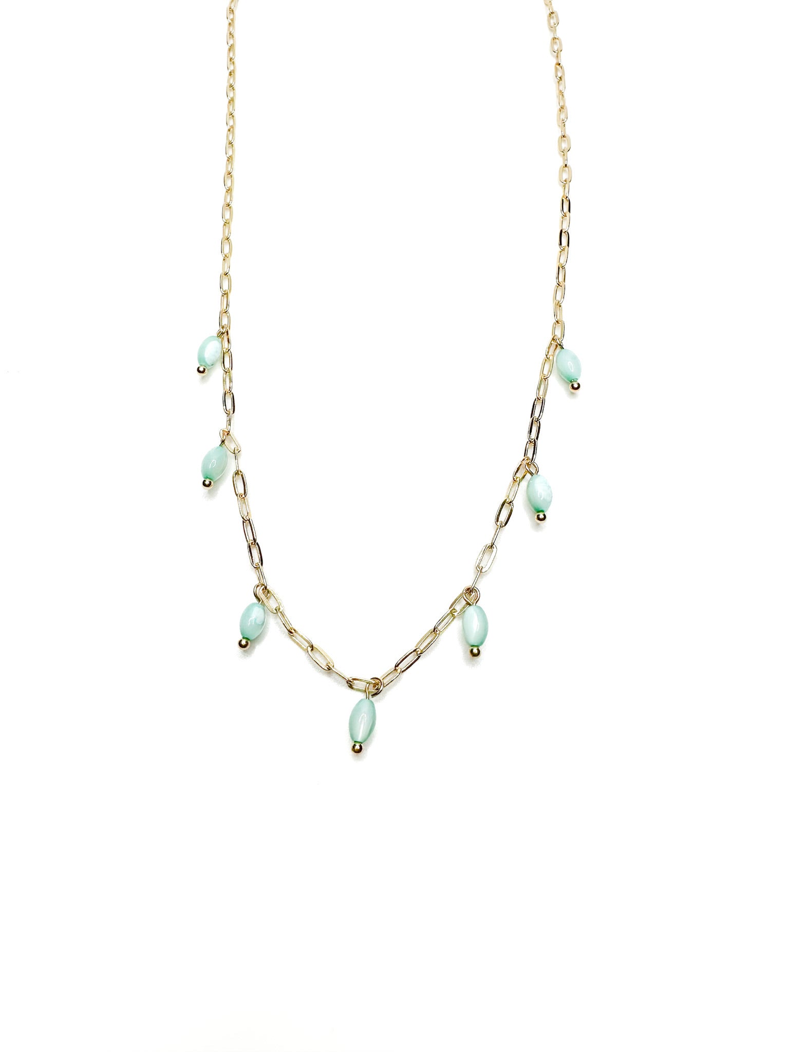 Delicate gold chain necklace with seafoam green bead drops laid flat on a white background