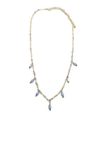 Gold necklace with small lavender drop beads evenly spaced along the front, laid flat on white background