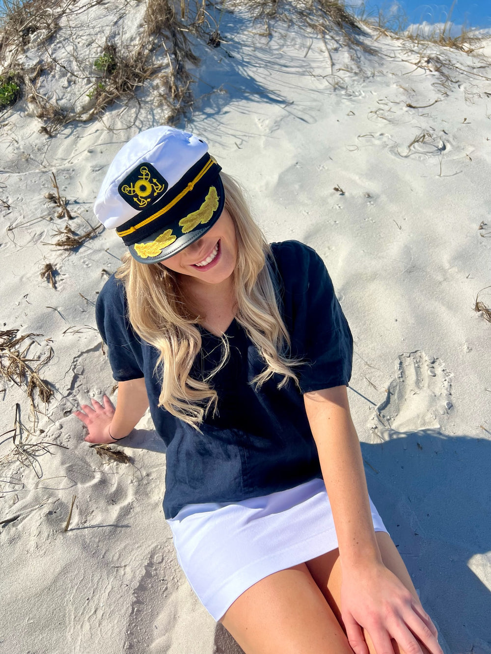 Woman wearing white captain hat in sand