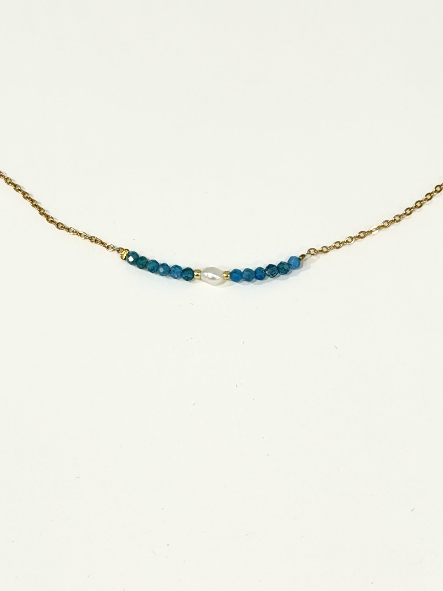 Blue apatite bead and freshwater pearl bar necklace on a gold-tone stainless steel chain, photographed on a white background.