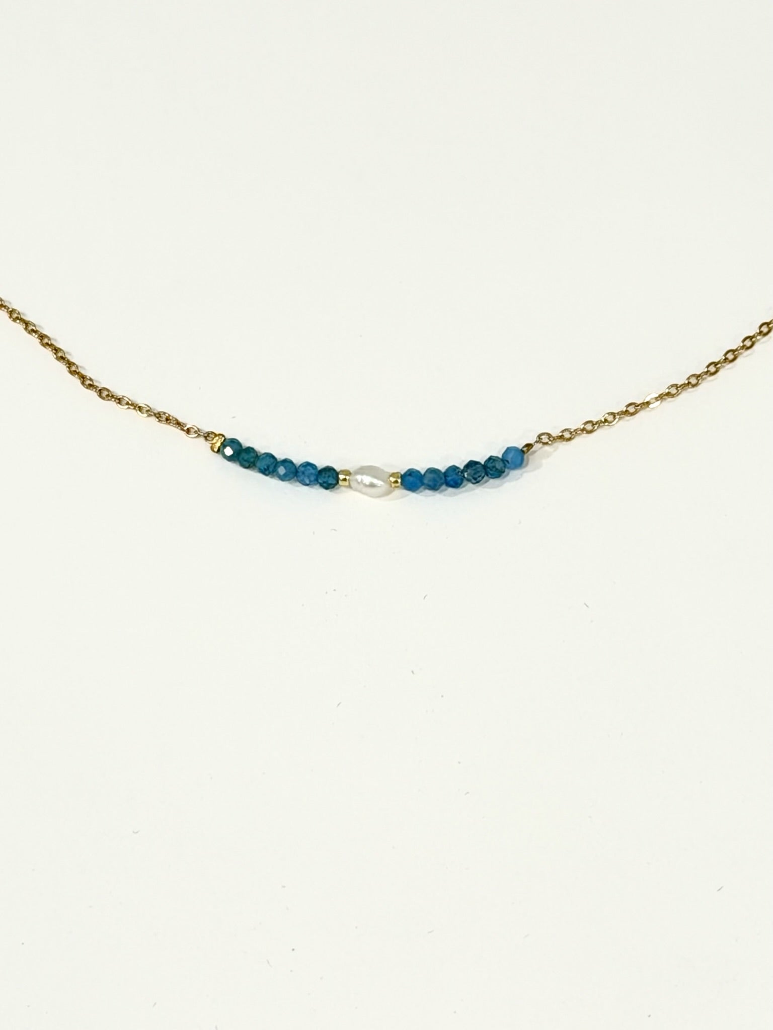 Blue apatite bead and freshwater pearl bar necklace on a gold-tone stainless steel chain, photographed on a white background.