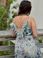 Woman wearing a floral dress with a white background and greenery
