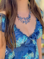 Woman wearing a blue floral dress with a necklace