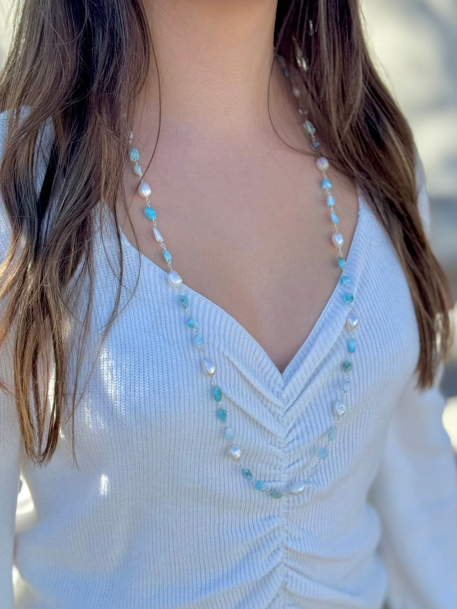 Adrina Amazonite and Freshwater Pearls long sterling silver necklace styled on a woman wearing a white v-neck ruched sweater.