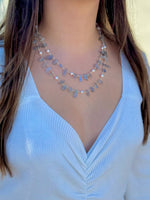Person wearing a light-colored sweater with a necklace
