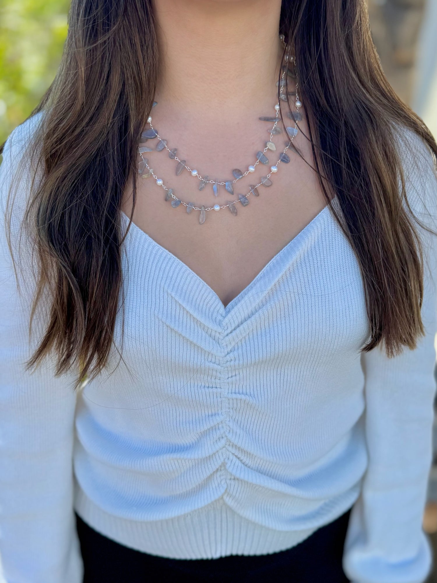 Person wearing a light-colored sweater with a necklace