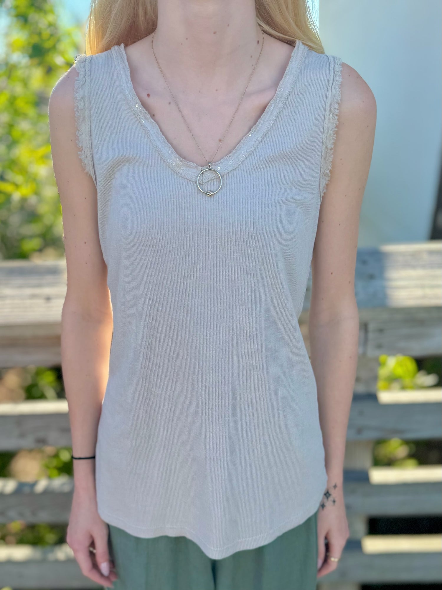 Front view of beige sequin-trim tank with V-neckline and soft knit fabric.