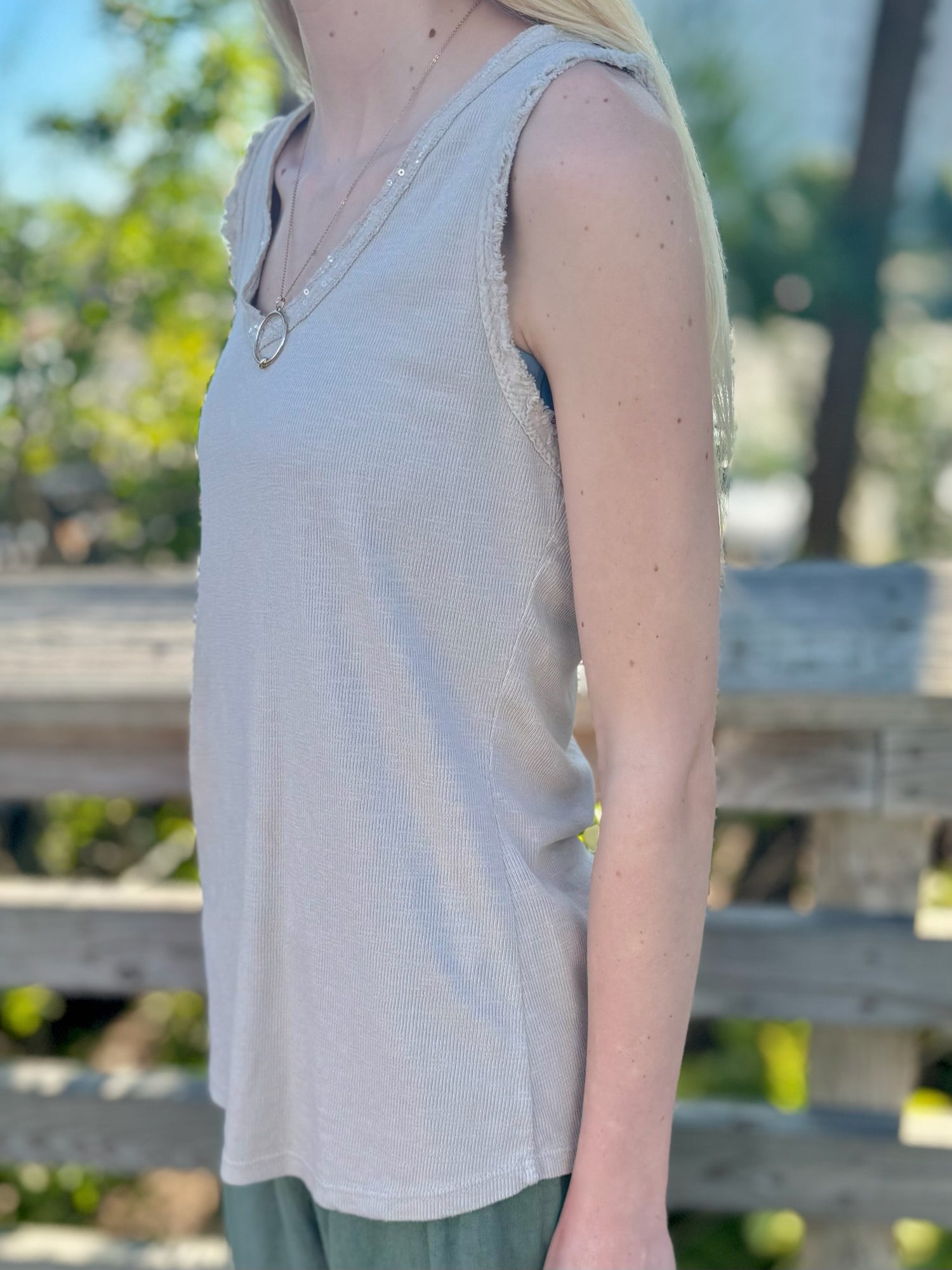 Side view of beige sequin tank showing raw-edge trim and lightweight knit texture.