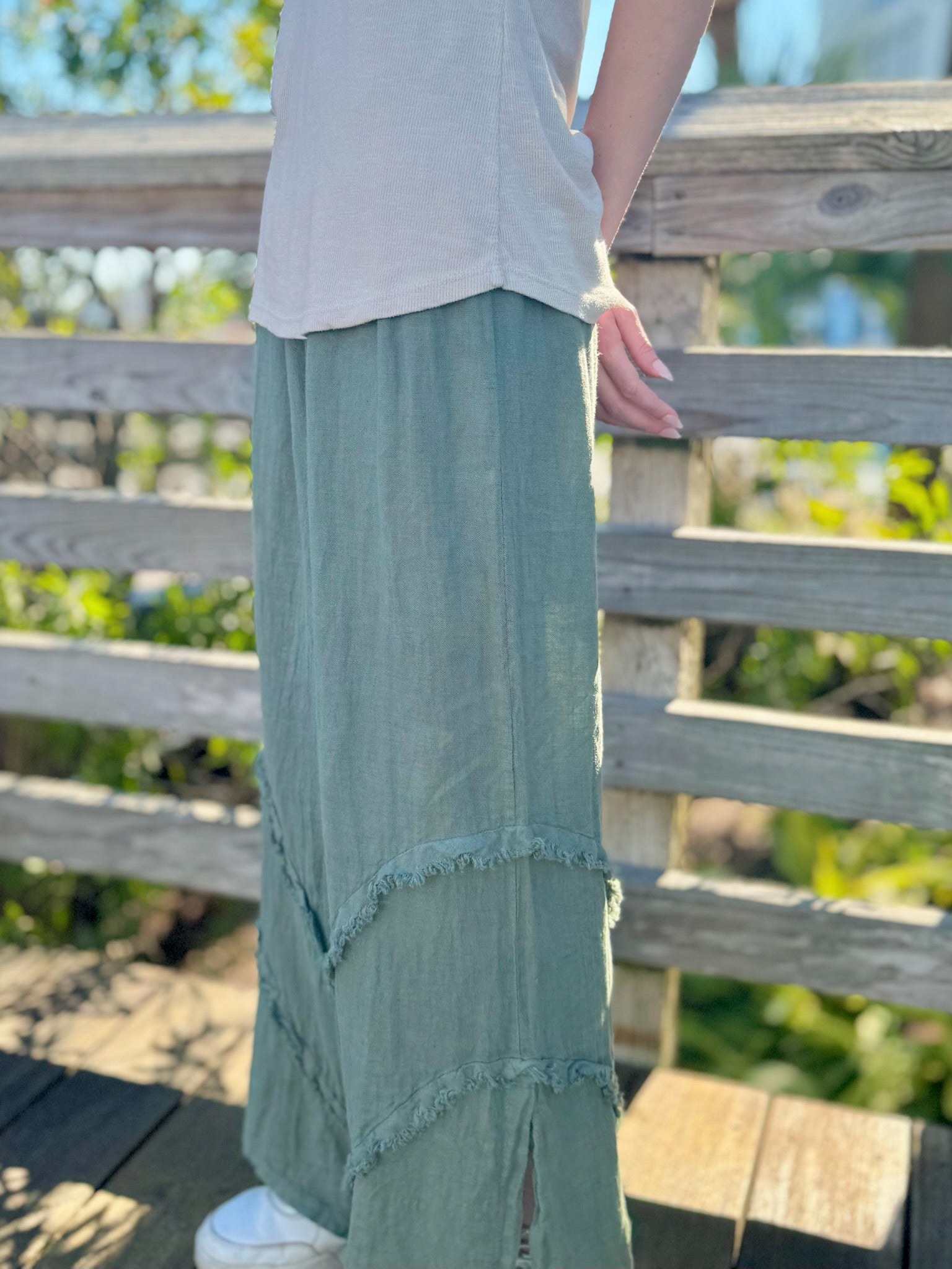 Side view of olive linen pants showing textured seams and side slit.