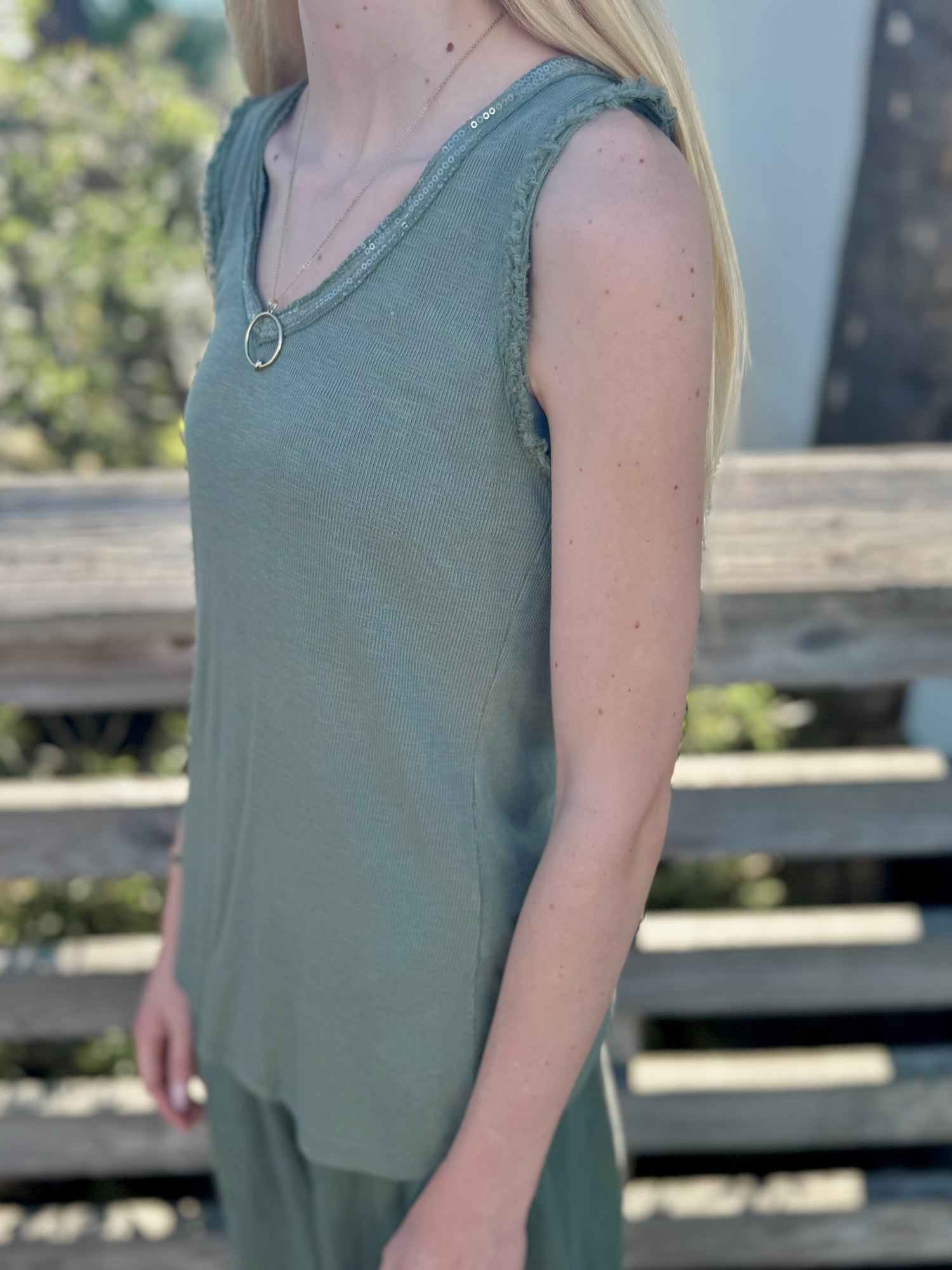Model wearing the Elisa Sequin Tank in olive, showing sequined neckline and raw-edge armhole detail from the side.