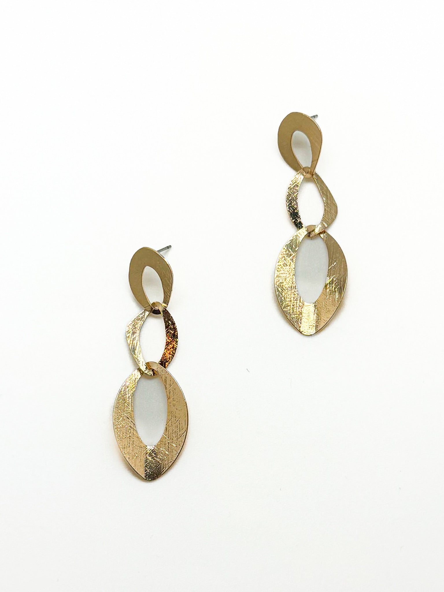 Gold dangly earrings with linked, open shapes on a white background