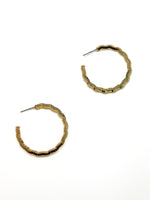 Gold hoop earrings with grooved design on a white background