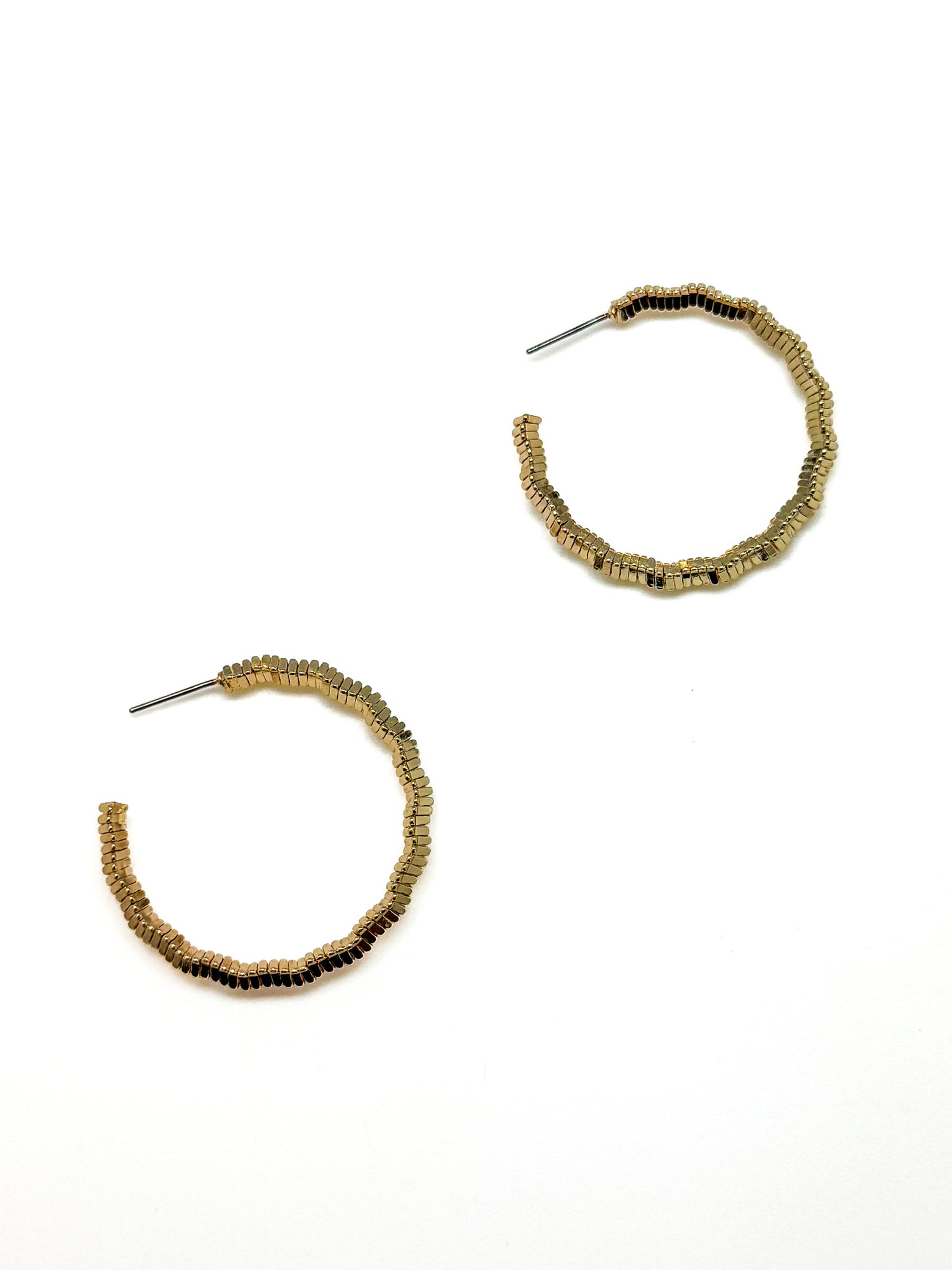 Gold hoop earrings with grooved design on a white background