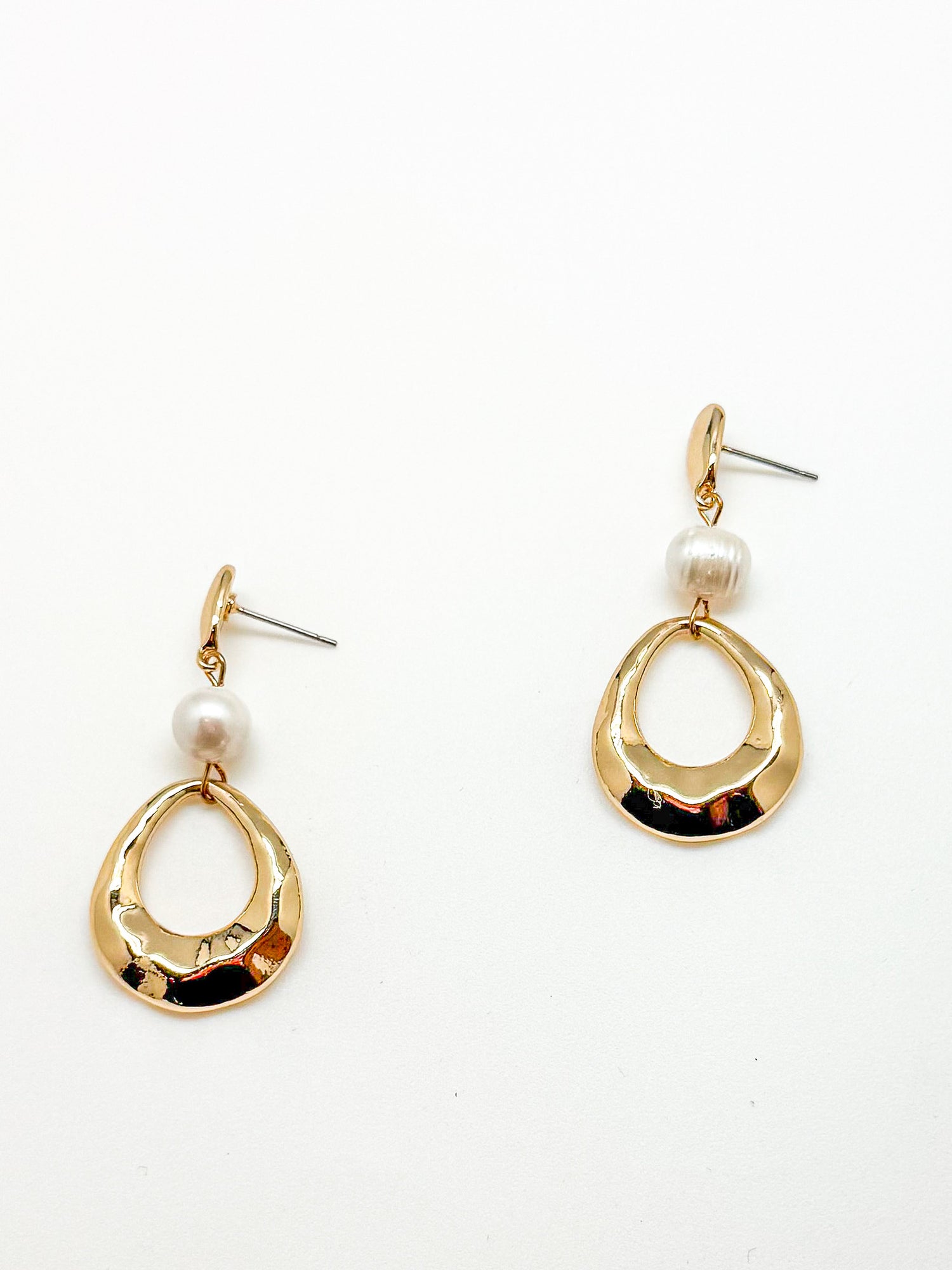Gold earrings with pearl drops on a white background