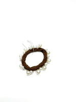 Hair tie with brown yarn and pearls on a white background
