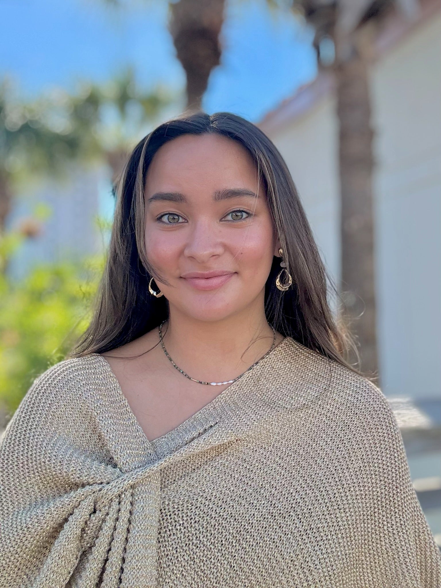 Woman wearing a beige sweater with a blurred outdoor background