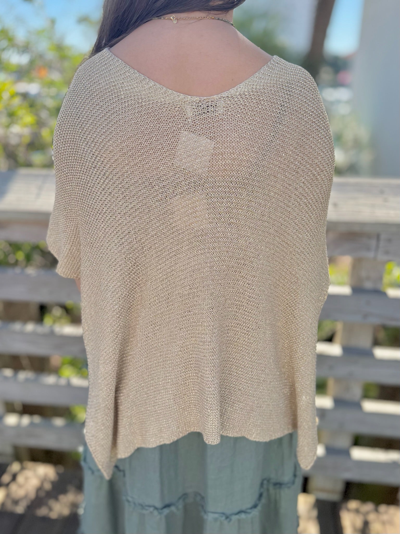 Beige knit top worn by a person with a blurred outdoor background