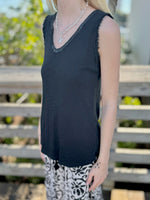 Person wearing a black sleeveless top with sparkly trim 