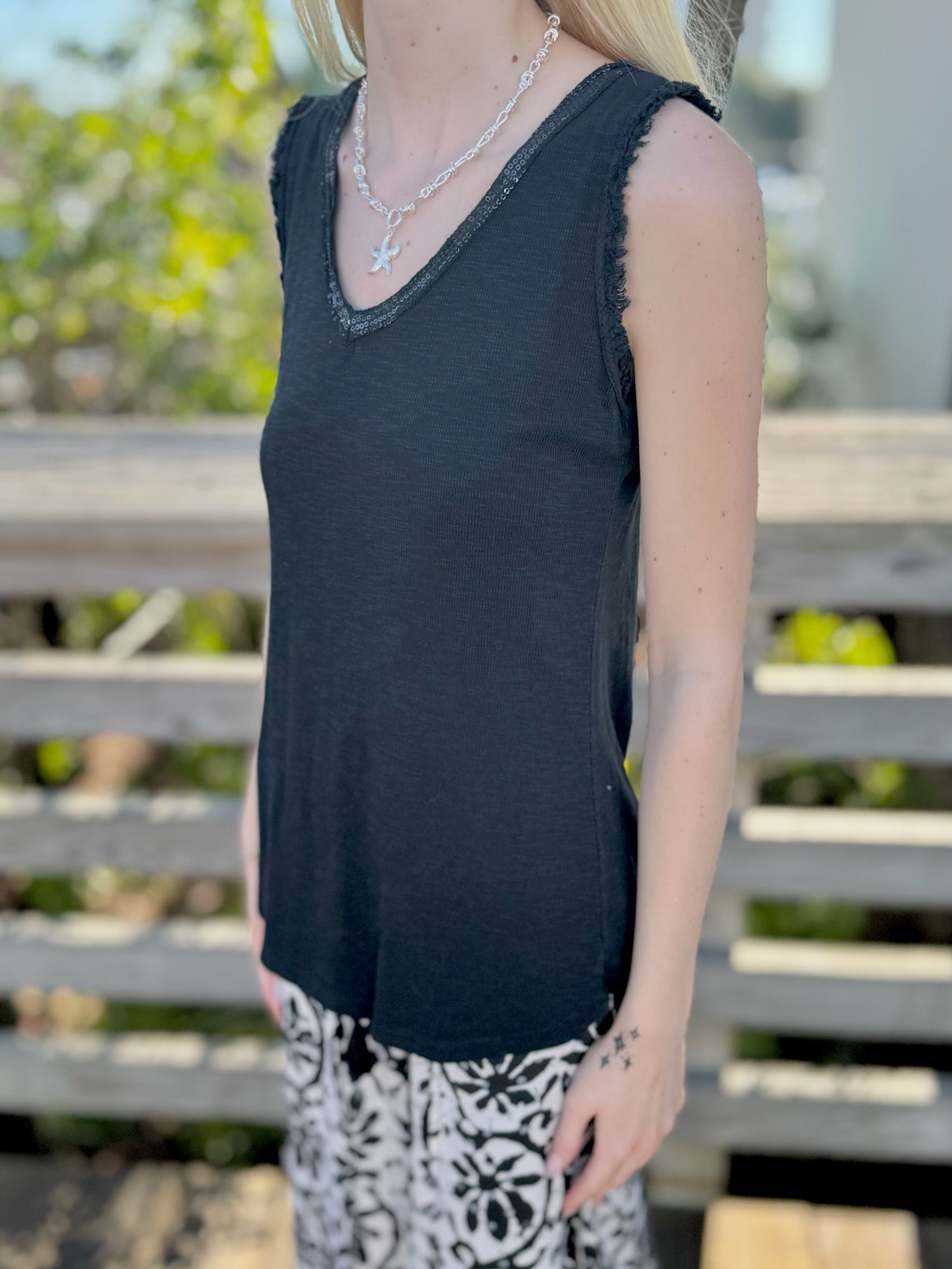 Person wearing a black sleeveless top with sparkly trim 