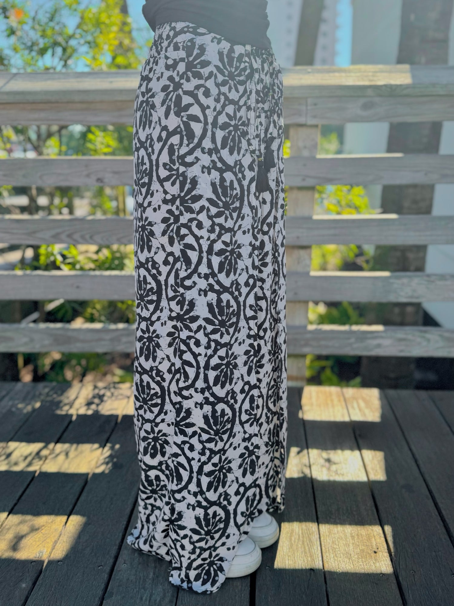 Side view of black-and-white printed wide-leg pants featuring a relaxed drape and adjustable waist tie.