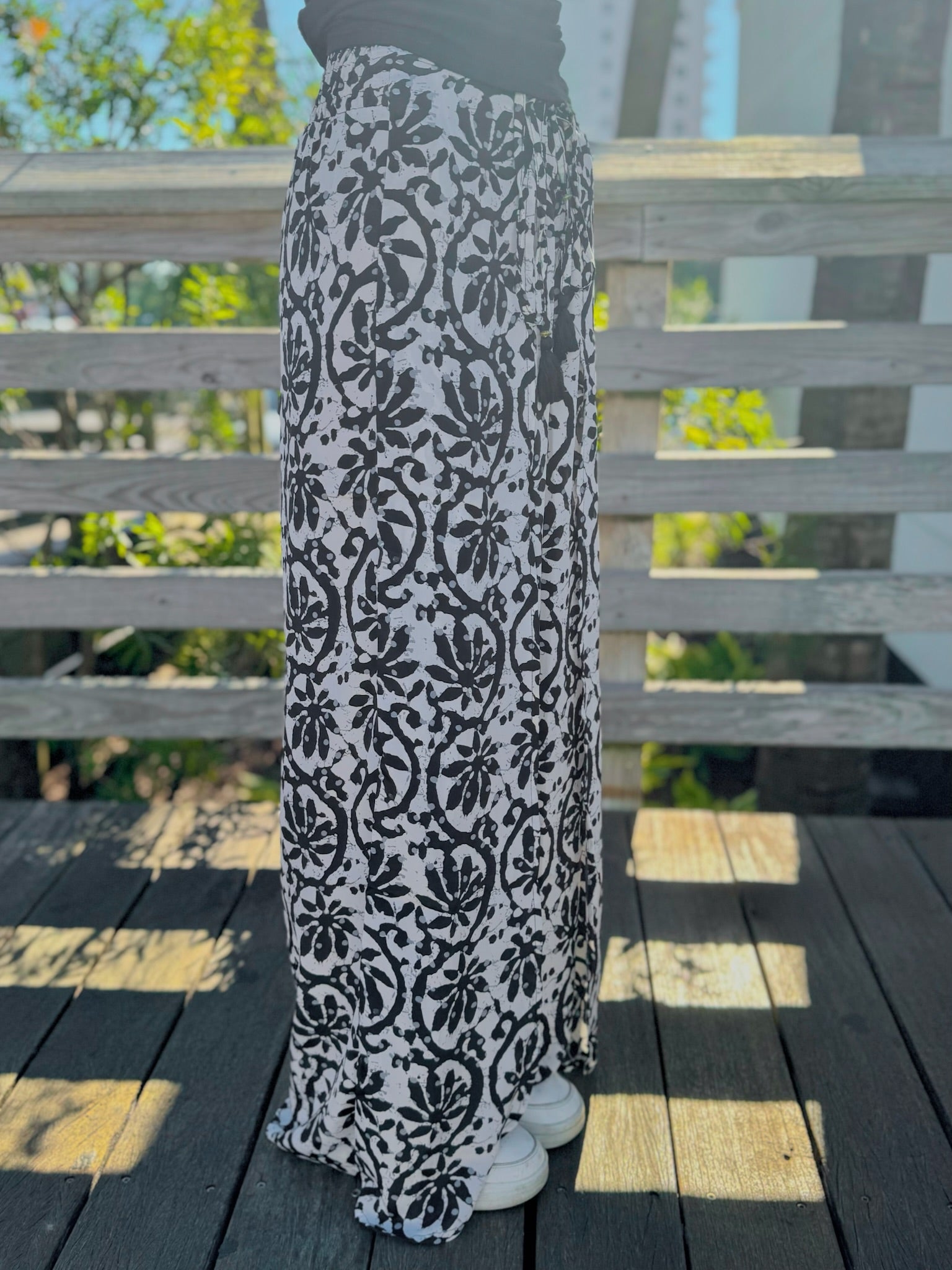 Side view of black-and-white printed wide-leg pants featuring a relaxed drape and adjustable waist tie.