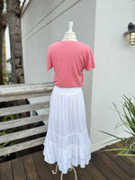White skirt paired with a coral V neck tee 