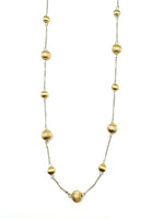 Gold plated sterling silver bead station necklace photographed on a white background