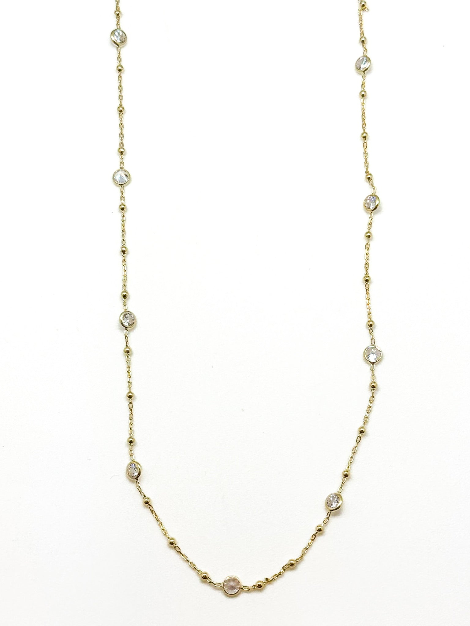 Gold necklace with small pearls on a white background