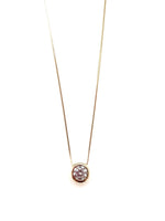 Gold necklace with a round pendant on a white background