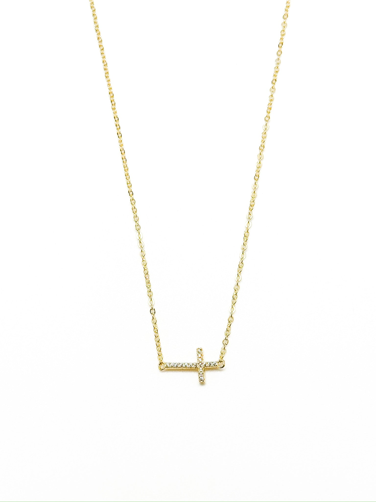 Gold necklace with a small cross pendant on a white background